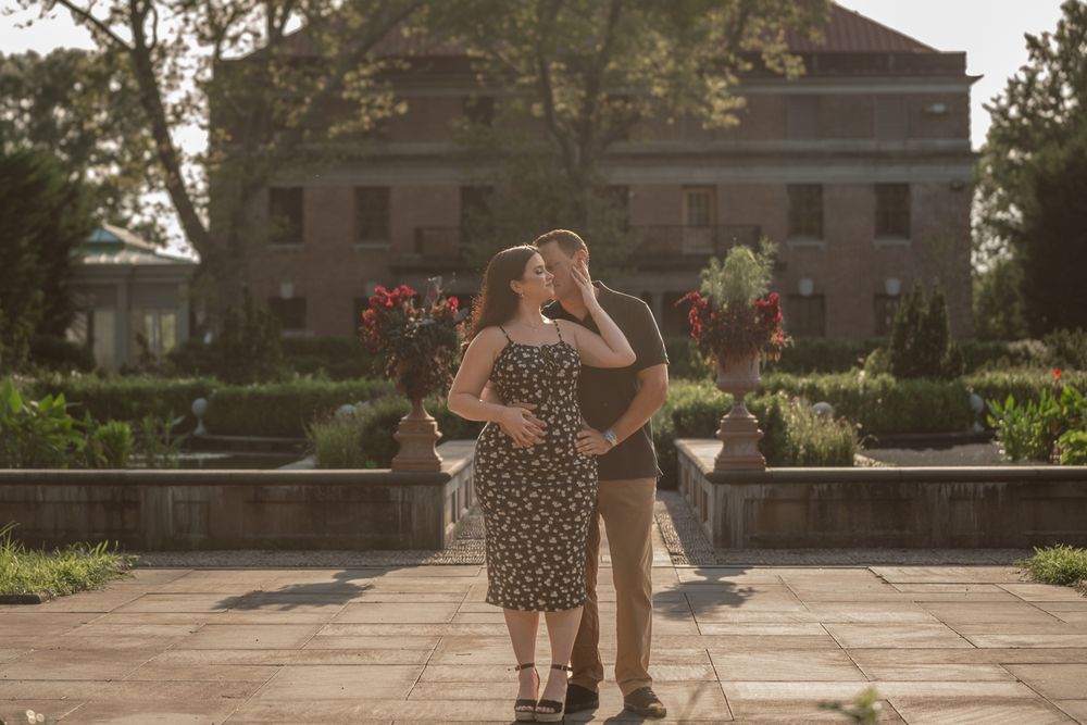 Two dancers perform an elegant spin on a sunlit terrace with historic architecture visible behind them.