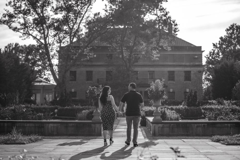 A silhouetted couple walking hand in hand in front of a historic building.