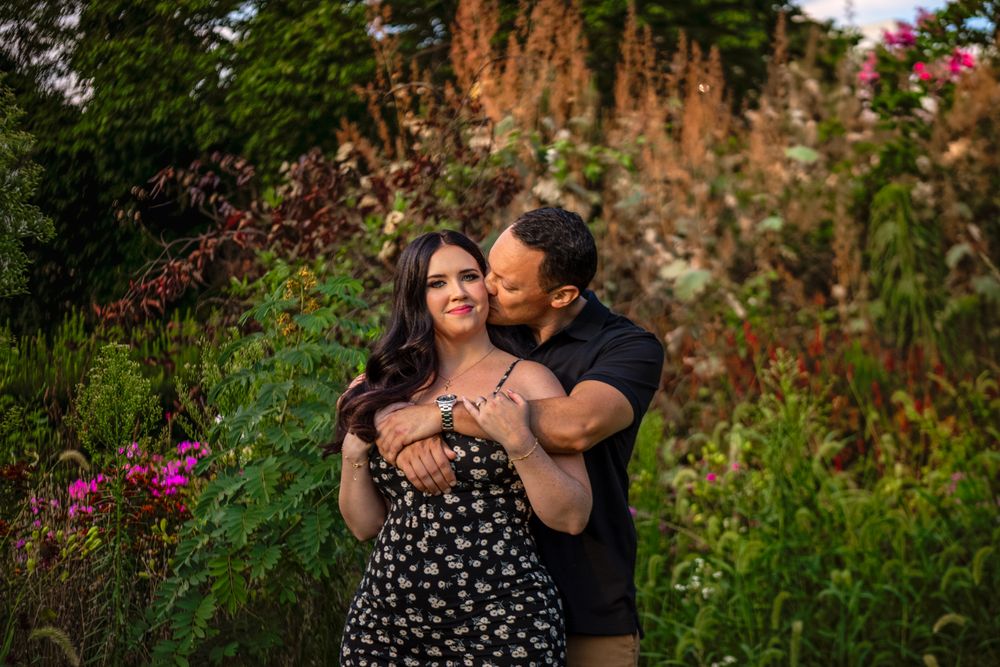 A tender moment captured between a couple in a vibrant flower garden during golden hour.
