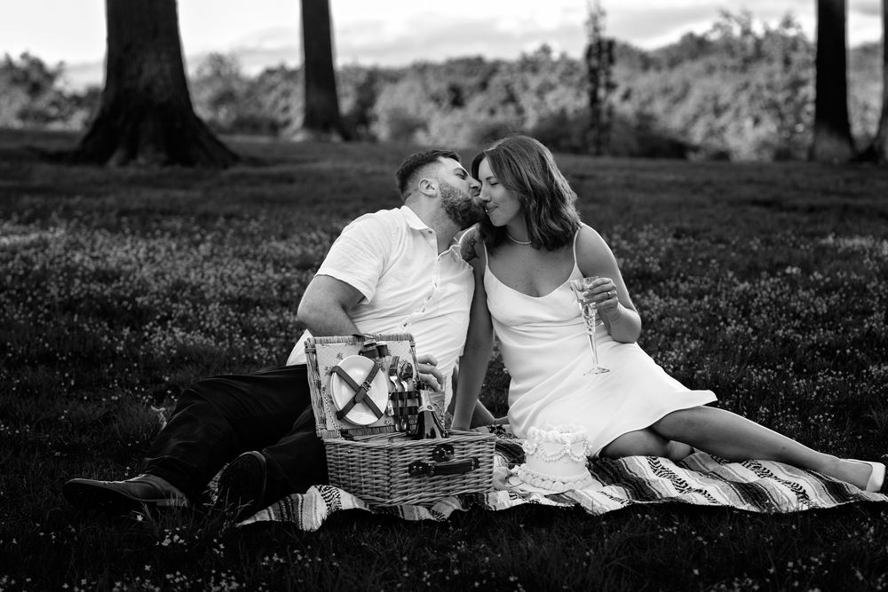Black and white photo of a couple relaxing together on a blanket during an outdoor picnic.