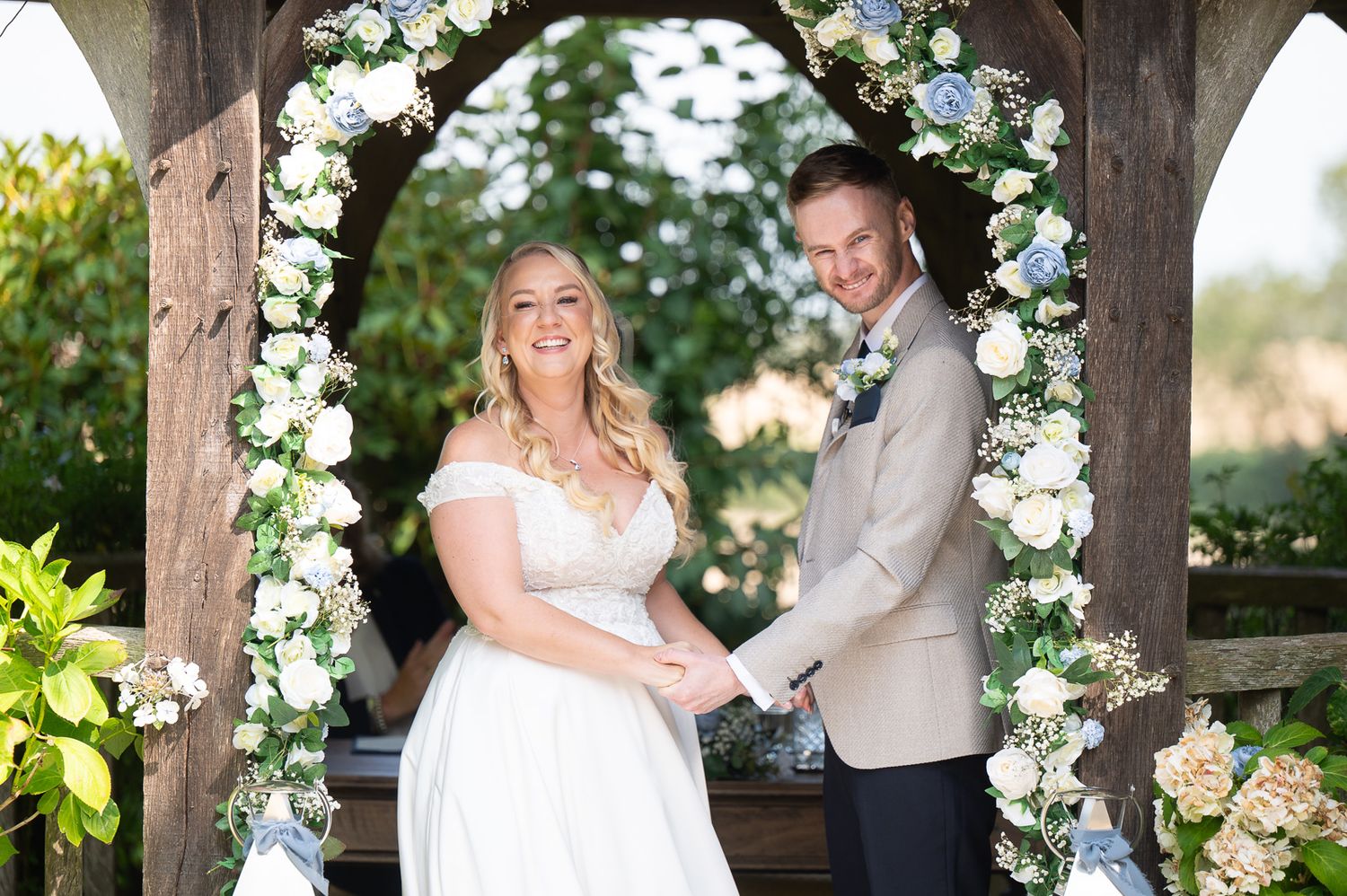Joyful wedding moment at Solton Manor – couple holding hands under gazebo, surrounded by family and friends.