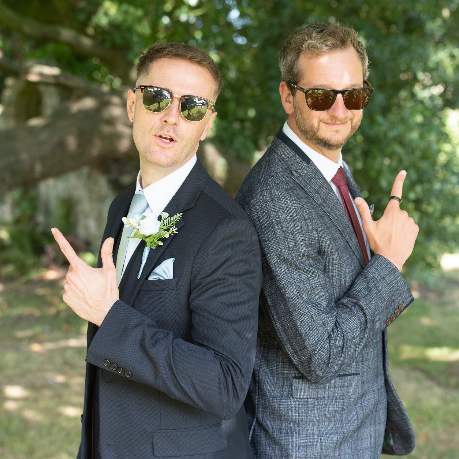 Groomsmen in suits pose playfully in a series of outdoor wedding photos with sunlit trees in the background.
