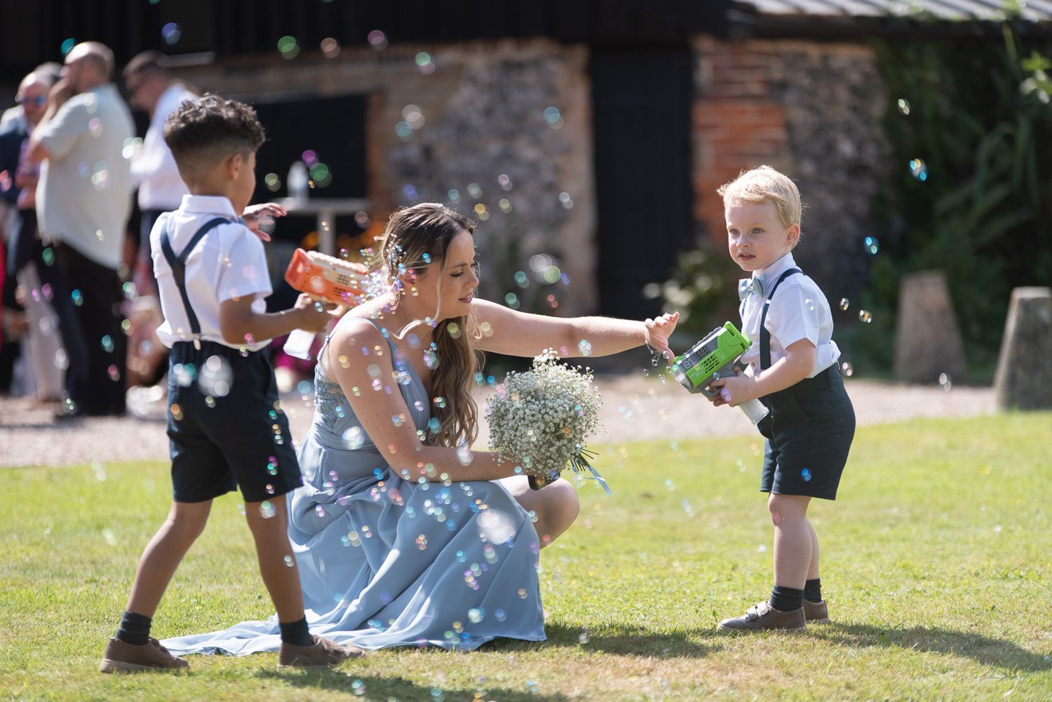 A joyful outdoor wedding moment with bubbles floating in the sunlit garden.