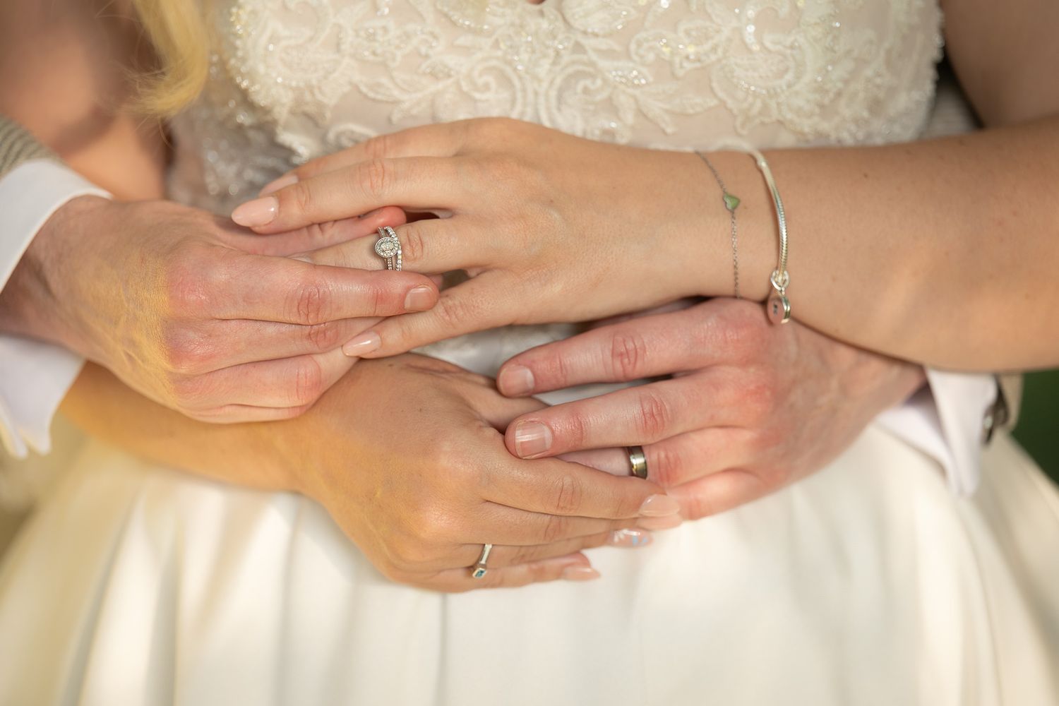 Close-up of bride and groom’s hands and wedding rings, golden hour lighting creating a warm romantic glow.