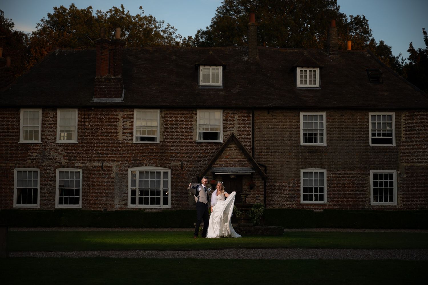 Bride and groom pose with attitude in front of Solton Manor at dusk, lit with dramatic off-camera flash.