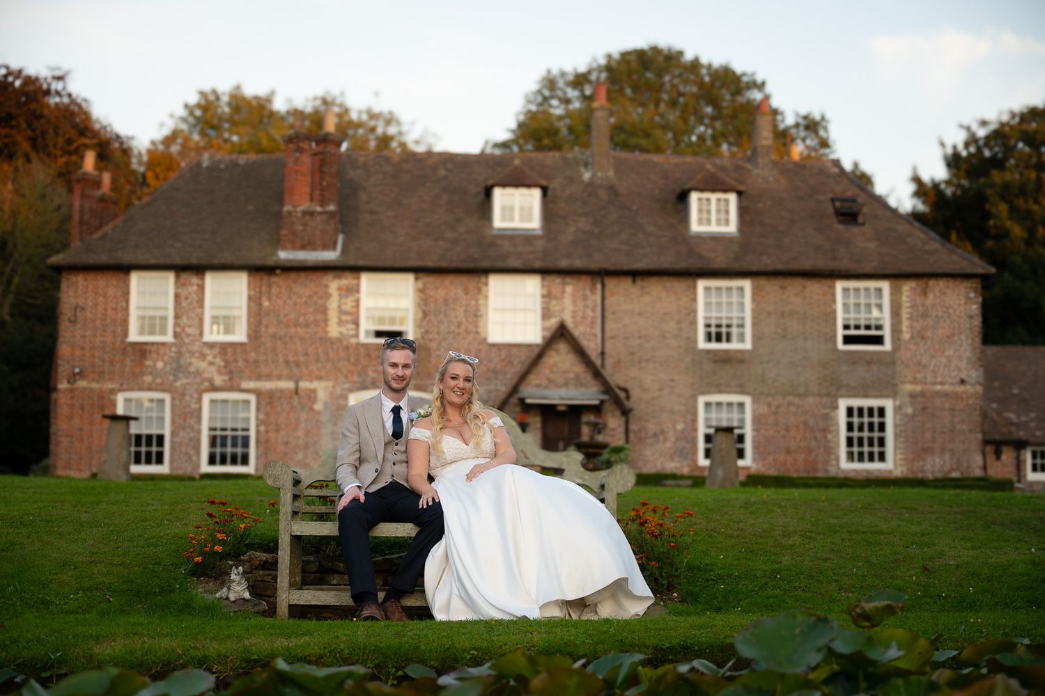 A wedding couple poses for romantic photos in front of a historic brick manor house.