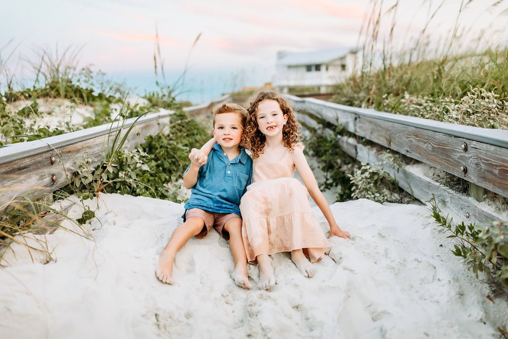 Family enjoying a relaxing moment together on a sandy beach boardwalk during sunset.