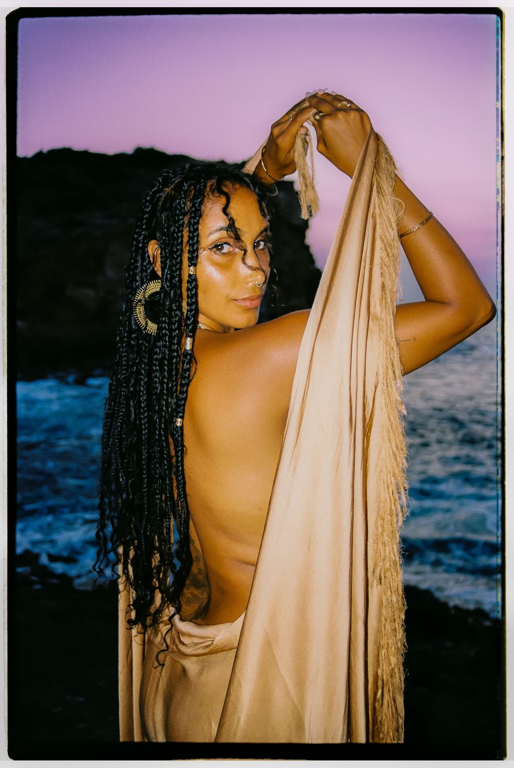 Artistic portrait series showing a figure draped in white fabric against an ocean sunset backdrop.
