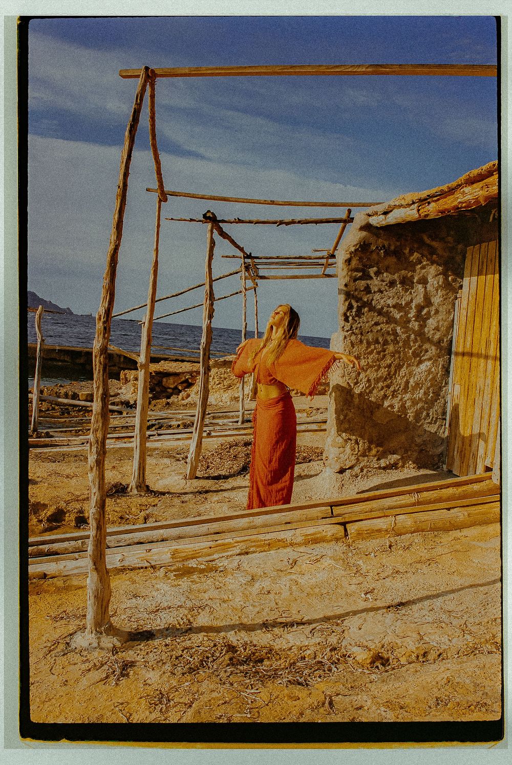 Rustic wooden poles and stone walls line a desert landscape under bright blue sky.