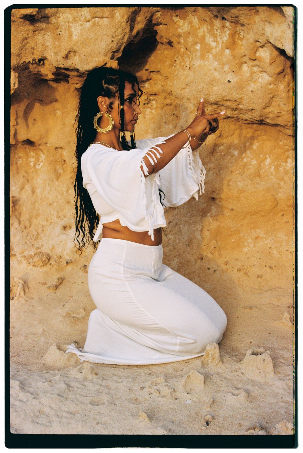 A person in white clothing poses gracefully against a textured beige stone wall in a series of artistic photographs.
