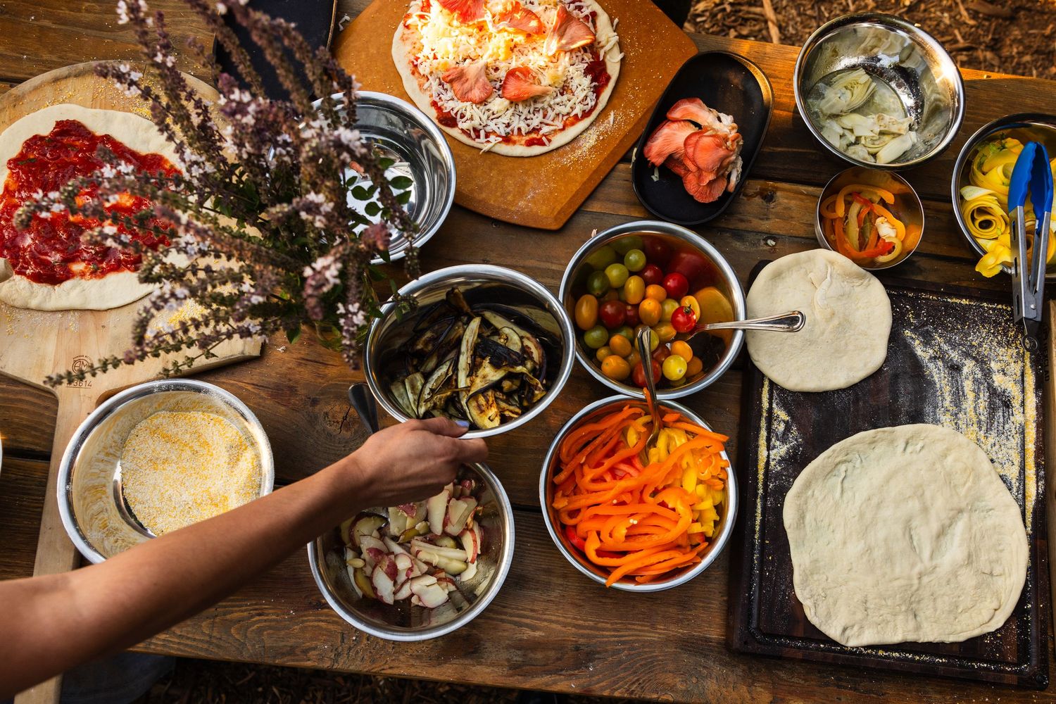 Overhead view of various colorful ingredients and bowls on a rustic wooden table for preparing a meal.