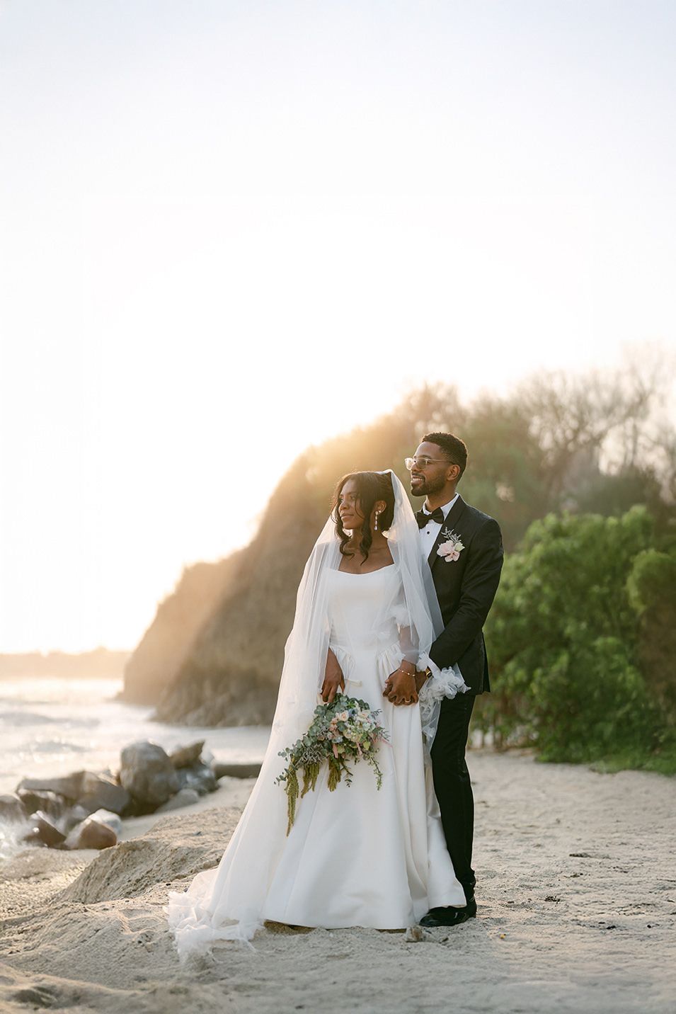 A couple shares an intimate moment under an archway adorned with pink bougainvillea flowers.