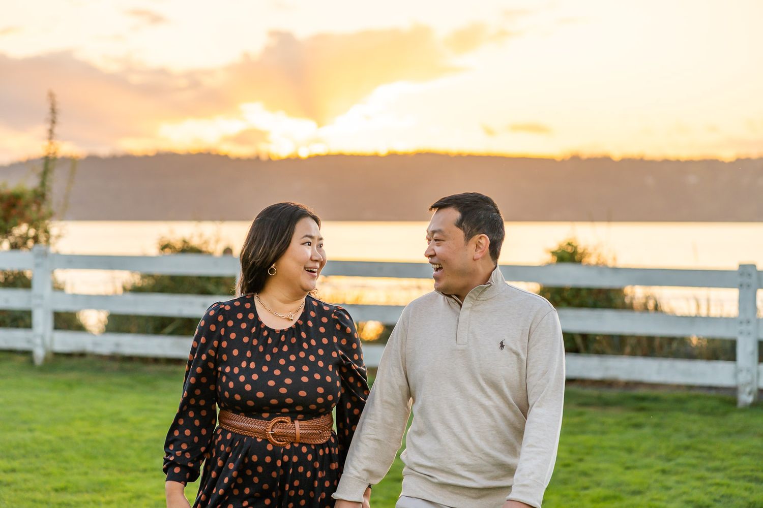 Husband and wife smile and walk together at sunset.