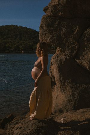 Silhouette against rocky cliffs by a serene lake during golden hour.