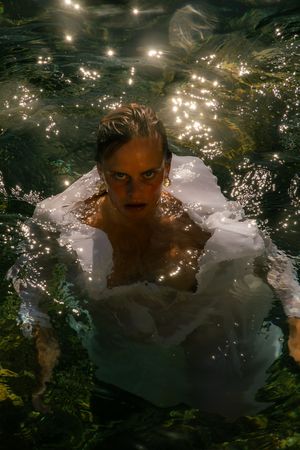 Dramatic underwater portrait with light reflections and ripples creating a moody atmospheric effect.