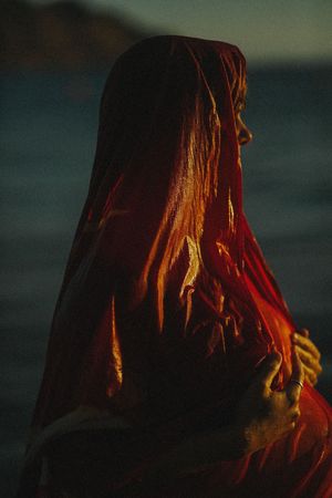 Warm sunset light illuminates flowing hair against a moody dark background.
