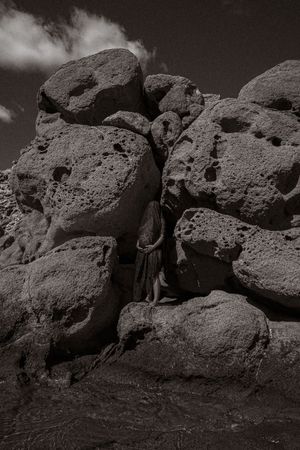 Jagged black rocks form a dramatic silhouette against a moody monochromatic background.