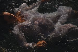 Dramatic underwater scene with light rays filtering through dark waves creating a moody atmosphere.