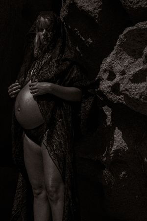 Artistic black and white photograph capturing figure among shadowy rock formations.