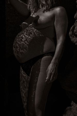 Artistic black and white close-up photograph of a figure in water with textured patterns.