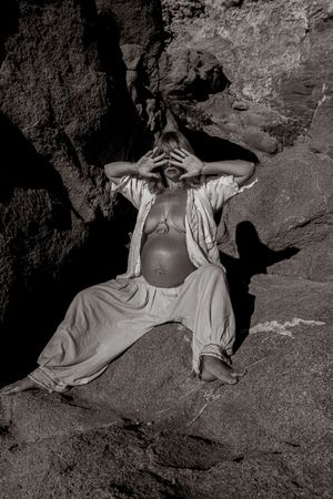 Artistic black and white photograph of someone reclining on rocky terrain.