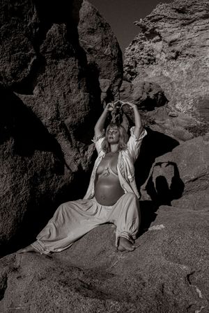 Artistic black and white photo of figure reclining among coastal rocks.