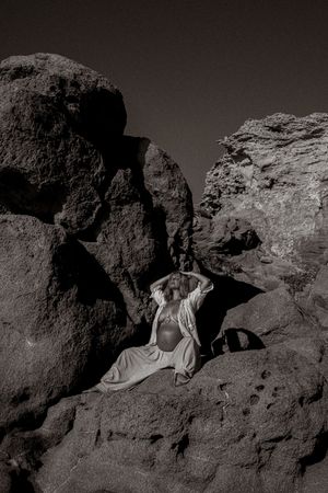 Monochromatic image of figure lying among dramatic rock formations in natural light.