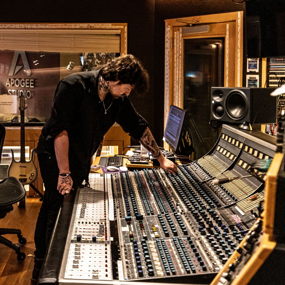 Audio engineer working at a large professional mixing console in a recording studio environment.
