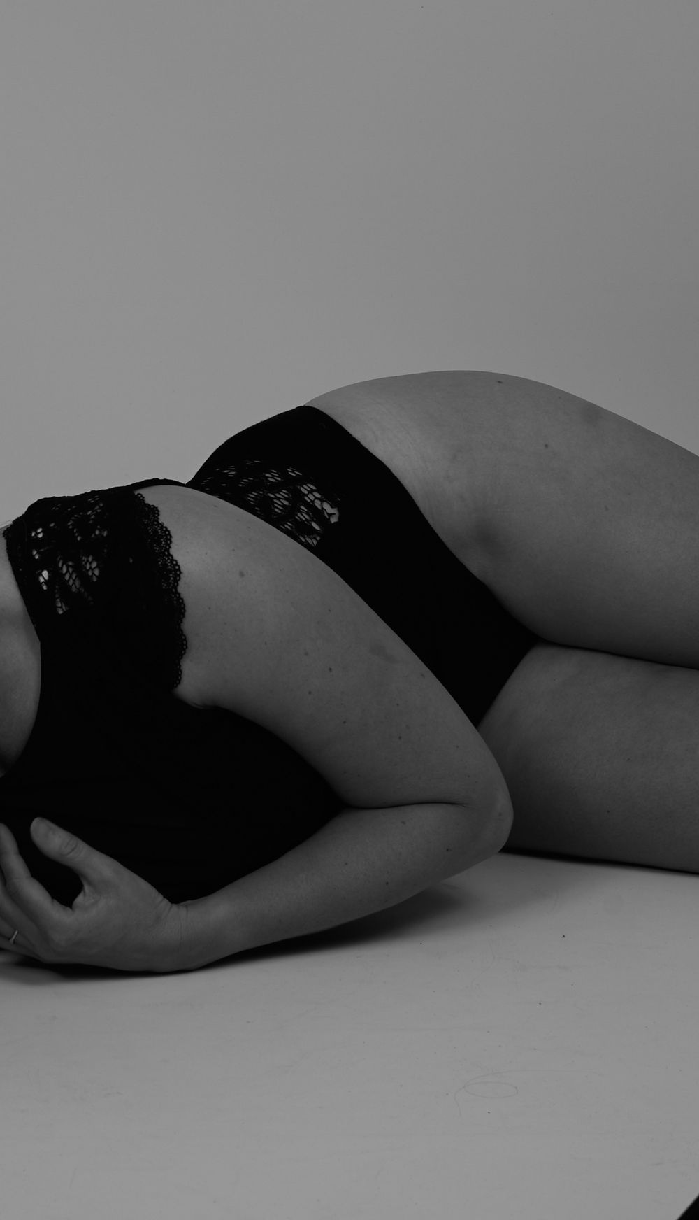 Black and white artistic photo series showing a reclining figure in dark lace against light background.