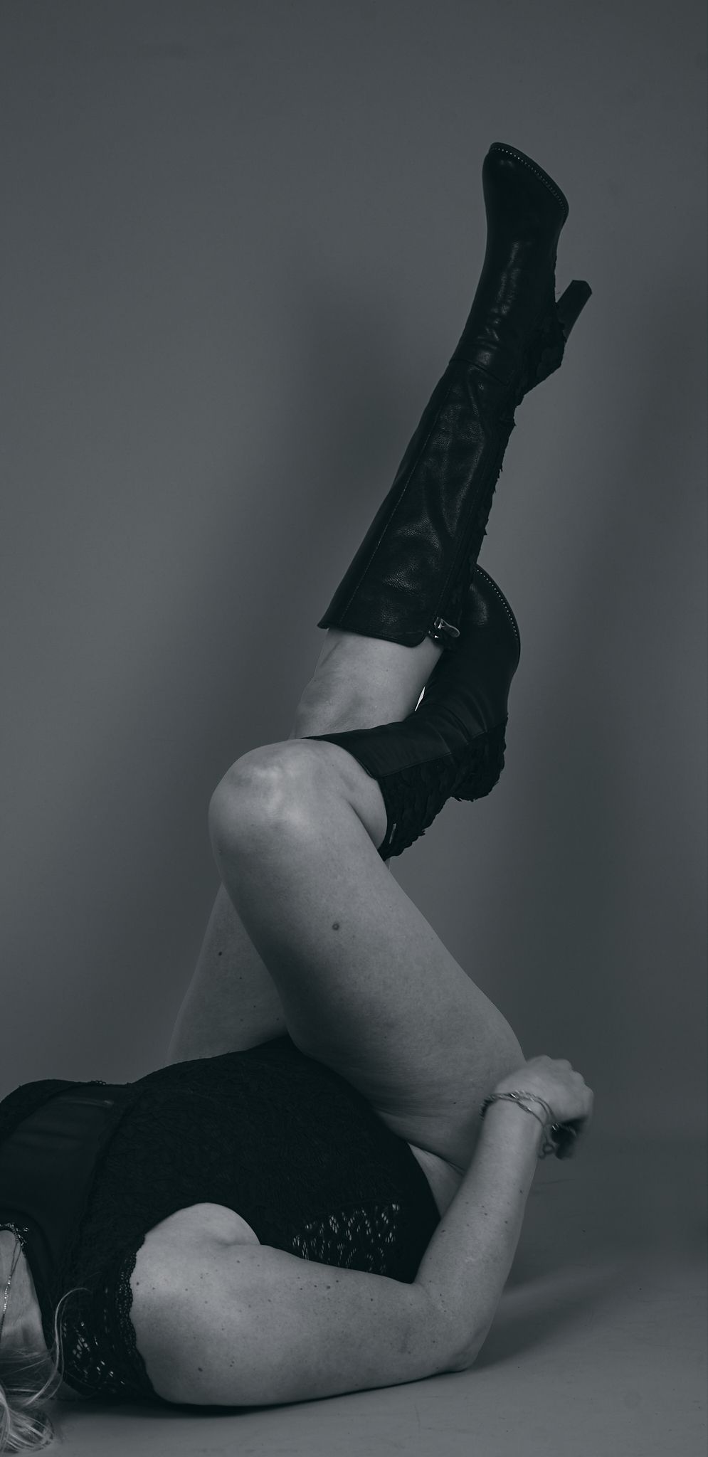 Artistic black and white photograph showing legs wearing black boots in various reclining positions.