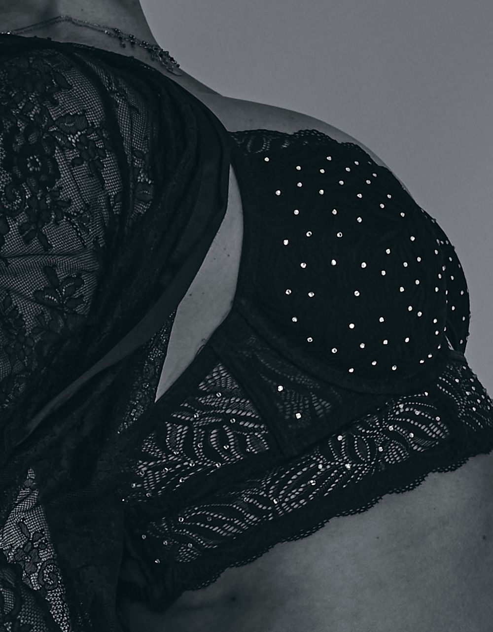 Close-up view of black lace bra details showing delicate embroidered patterns and scalloped edges.