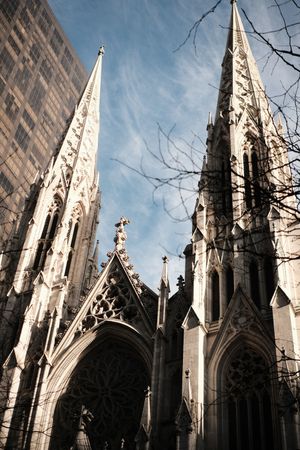 Gothic spires of St. Patrick's Cathedral reach toward blue sky in New York City.