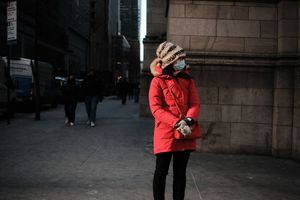 Person in bright red winter coat walking along city street.