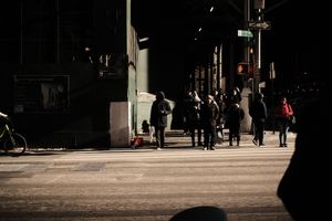 Silhouetted figures walking through a dark urban passageway.