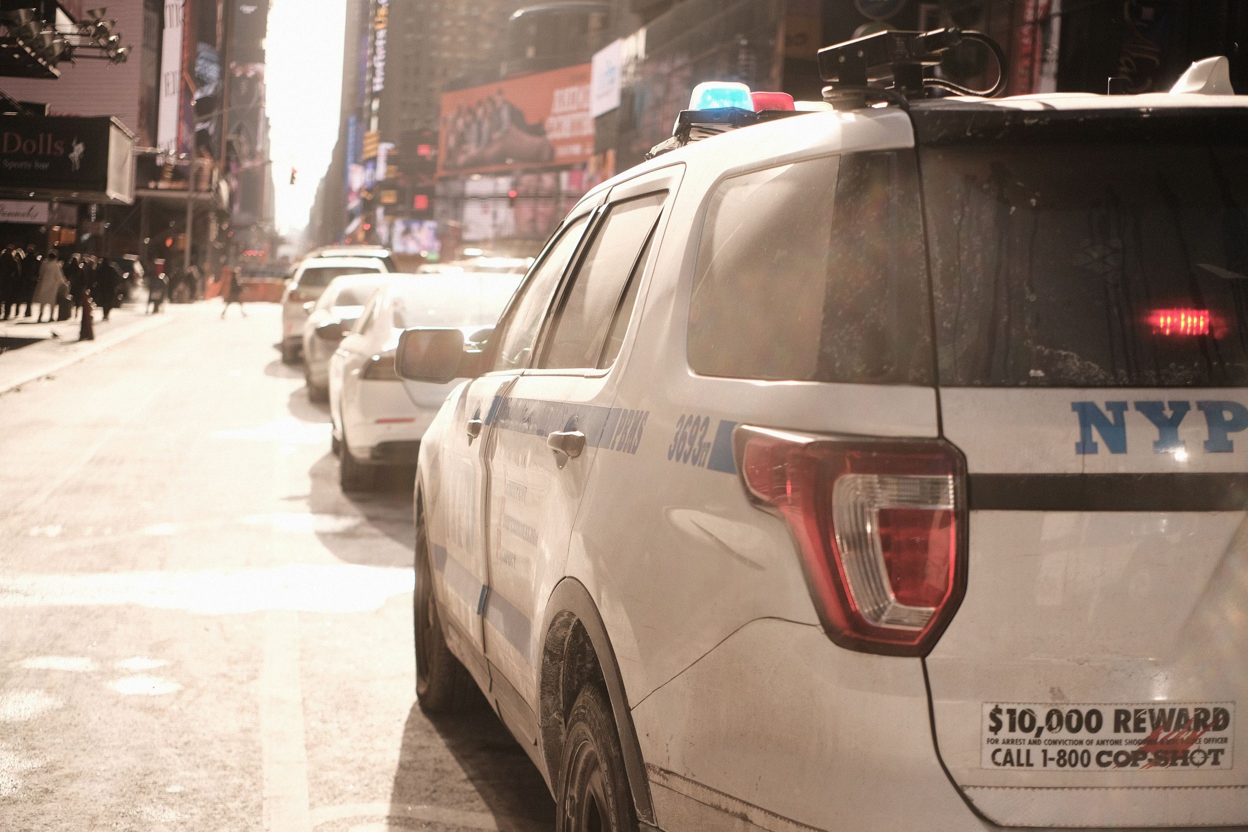 Row of parked police vehicles on a snowy city street.