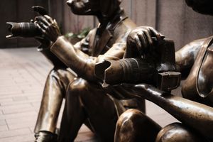 Bronze statue details showing hands and metallic textures in dramatic lighting.