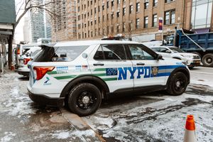Row of NYPD police cars parked on snowy street in New York City.