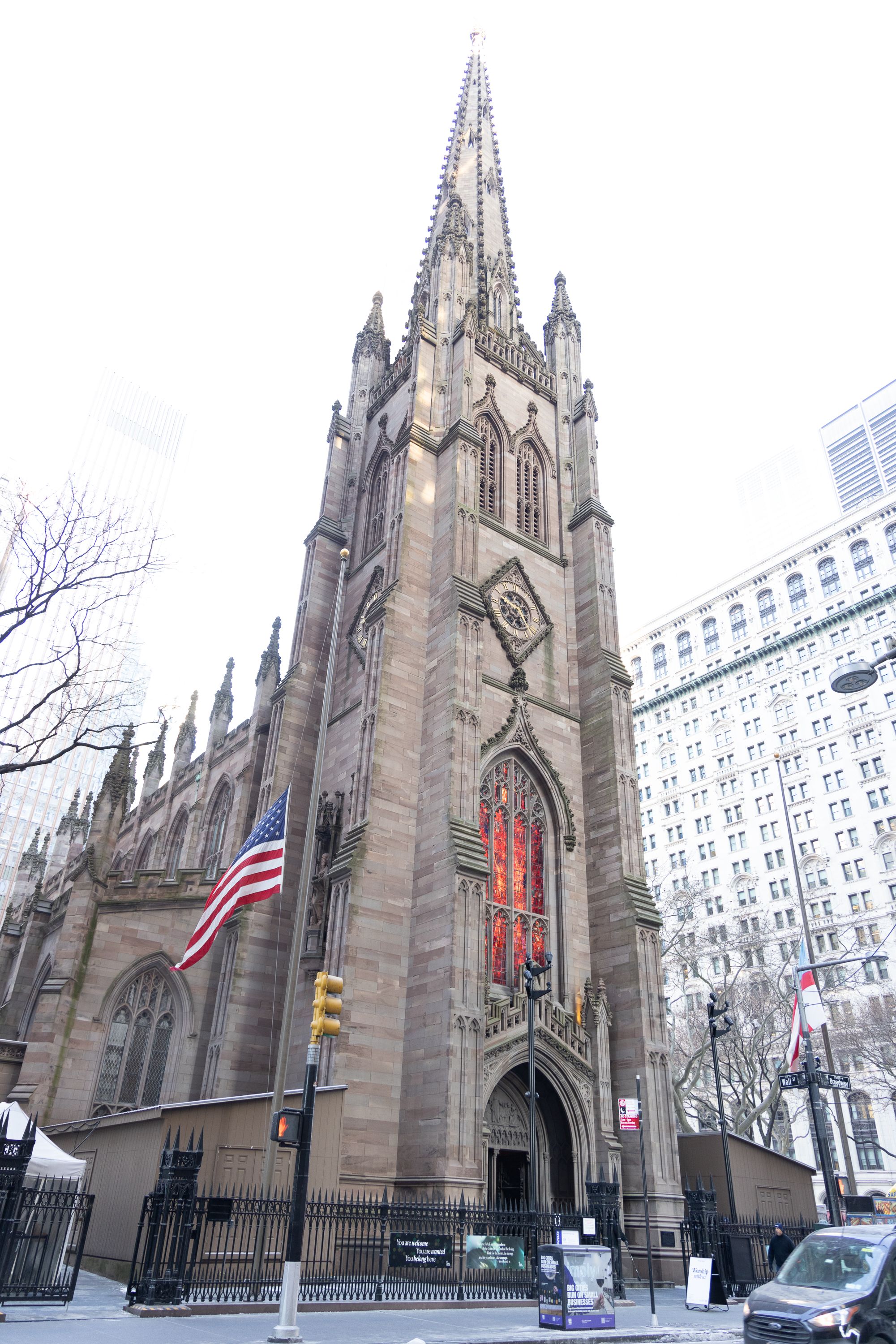 Gothic revival Trinity Church in New York City with American flags flying outside.