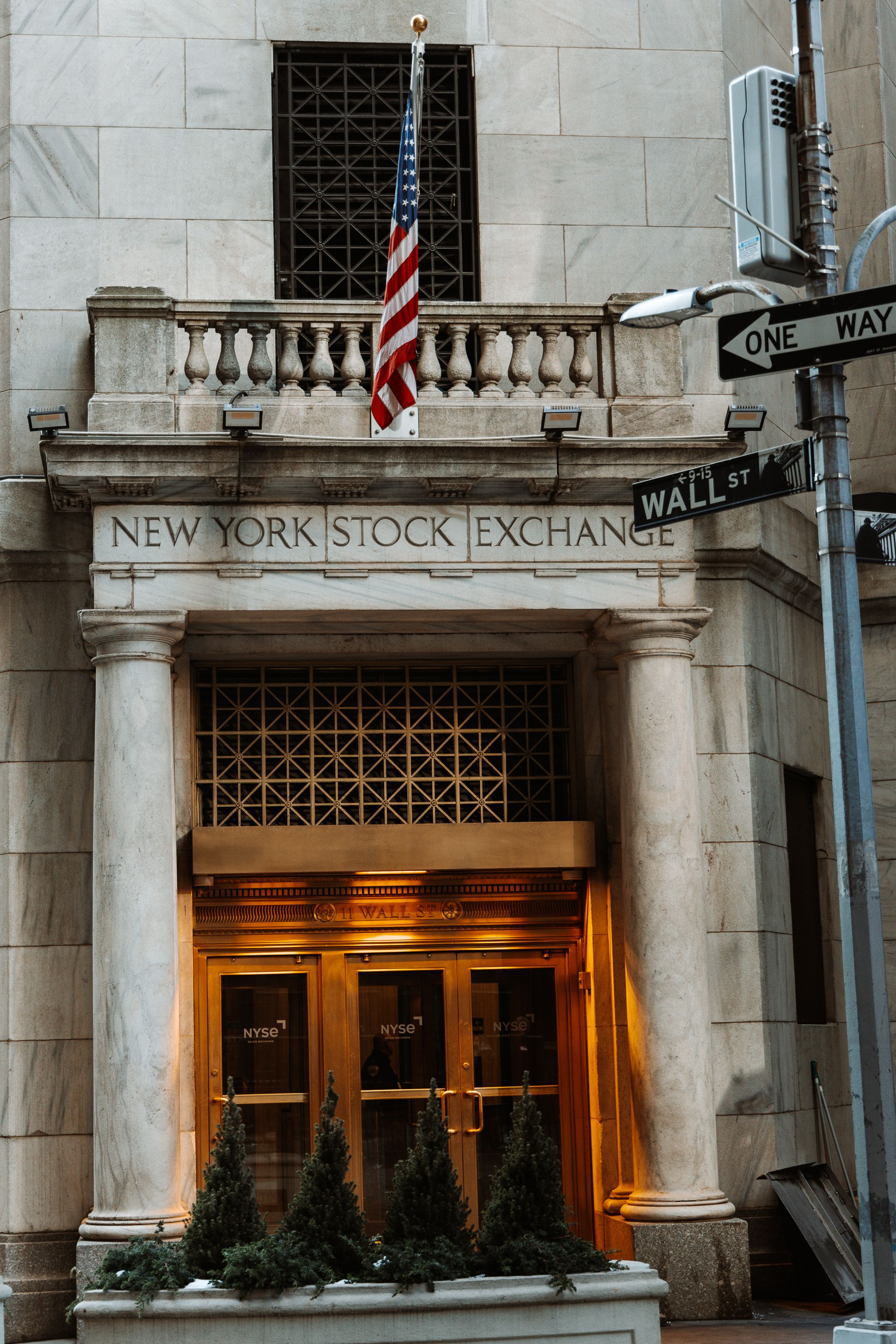 Entrance to the New York Stock Exchange building with illuminated columns and American flag.