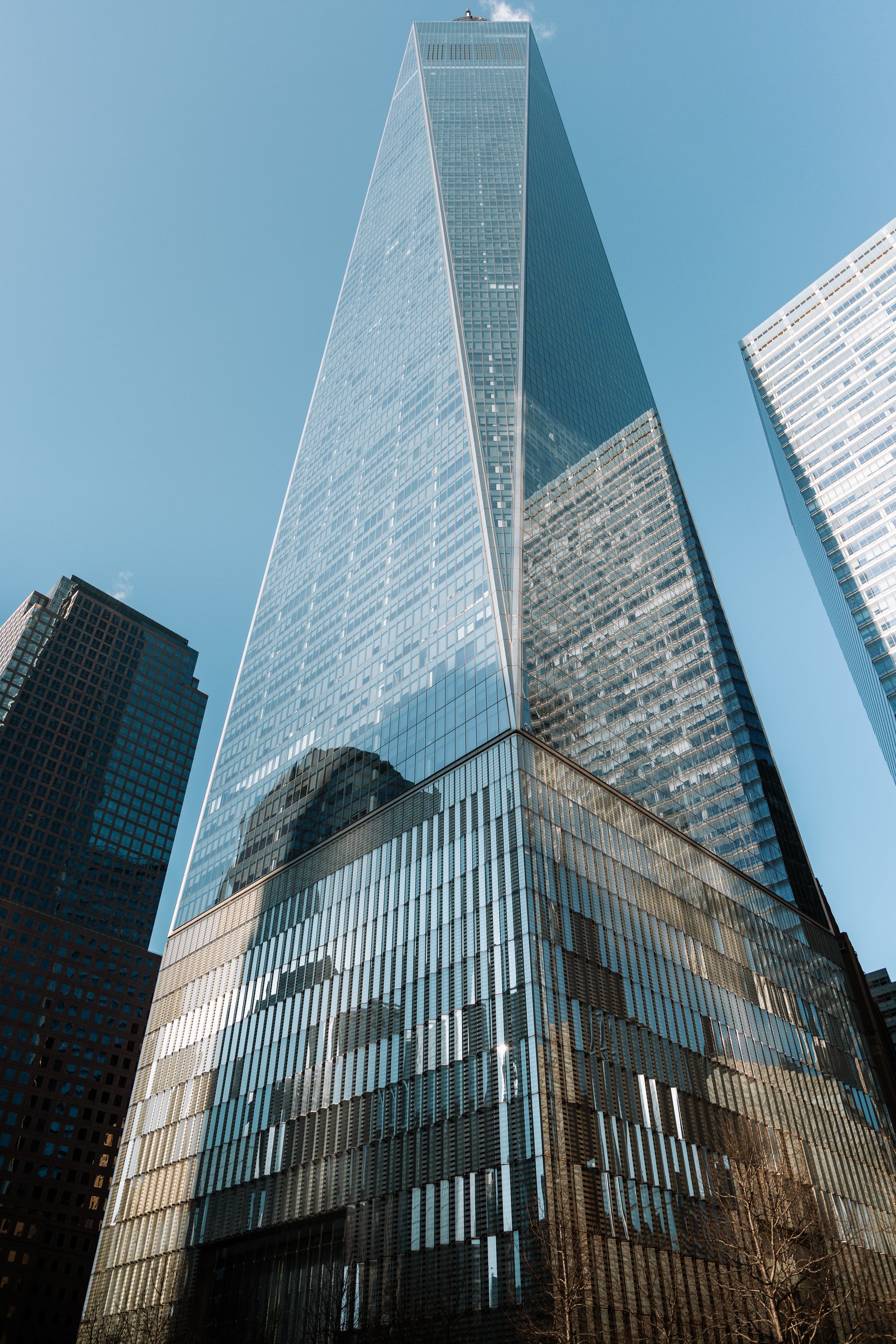 Modern glass skyscraper reflecting sunlight against blue sky in downtown Manhattan.