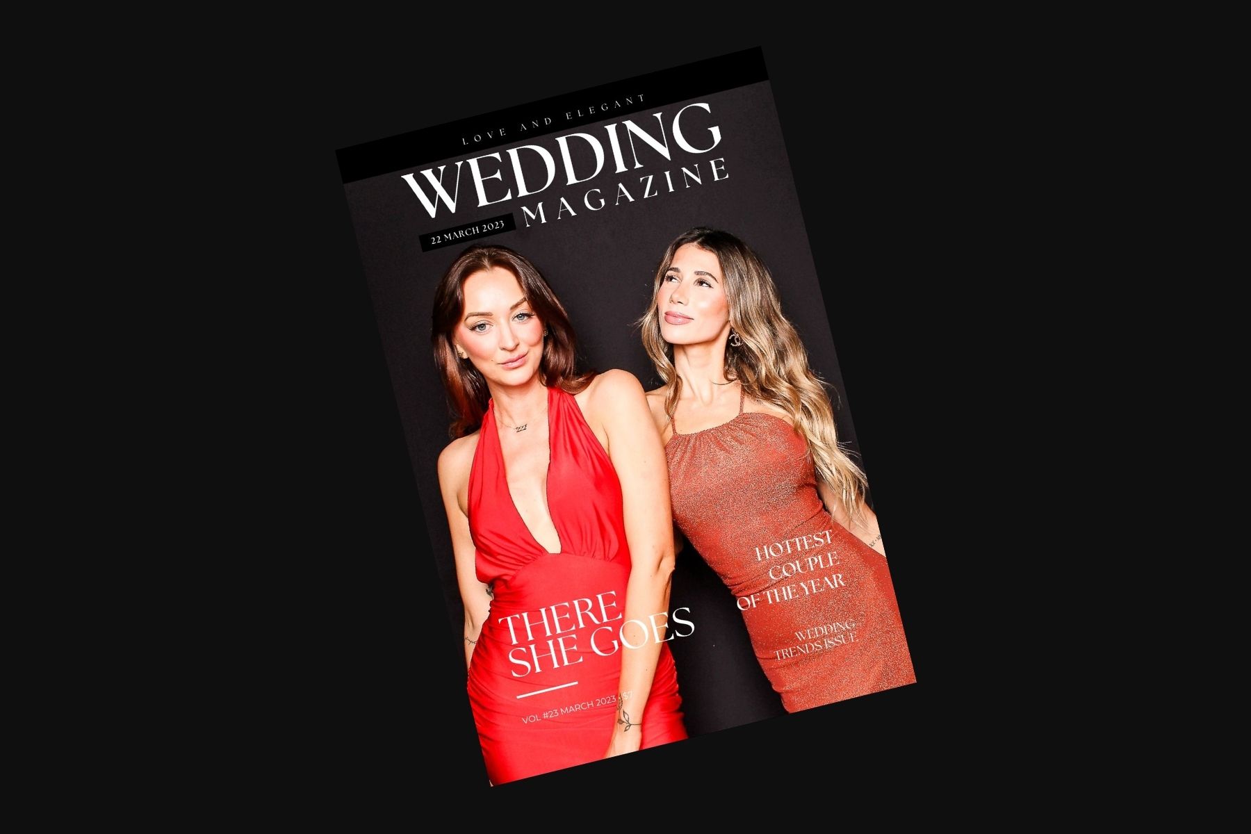 Two people pose together wearing vibrant red outfits at a wedding-themed event.