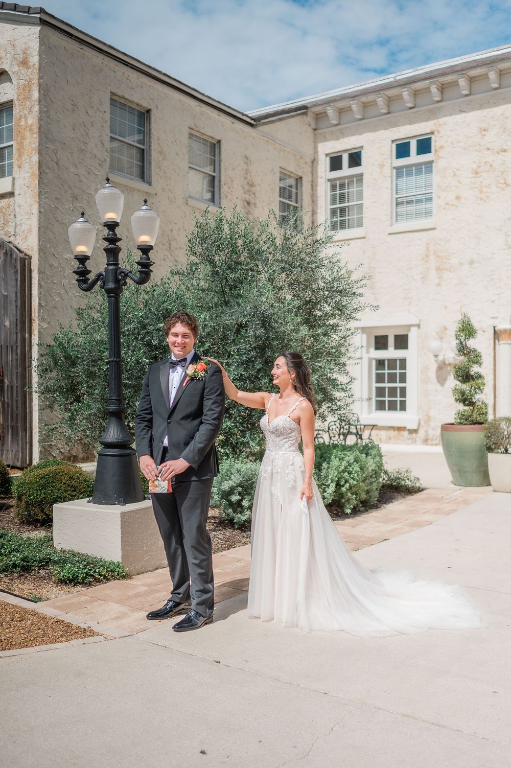 A wedding couple poses for portraits outside a grand stone building with elegant architecture.
