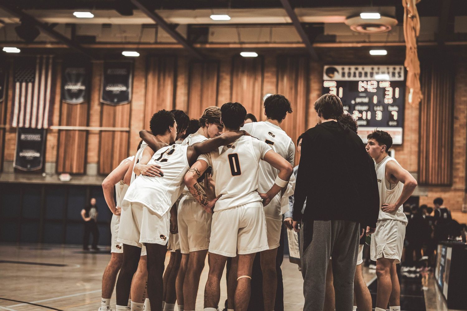 Basketball players line up along the sideline during a game in an indoor gymnasium.