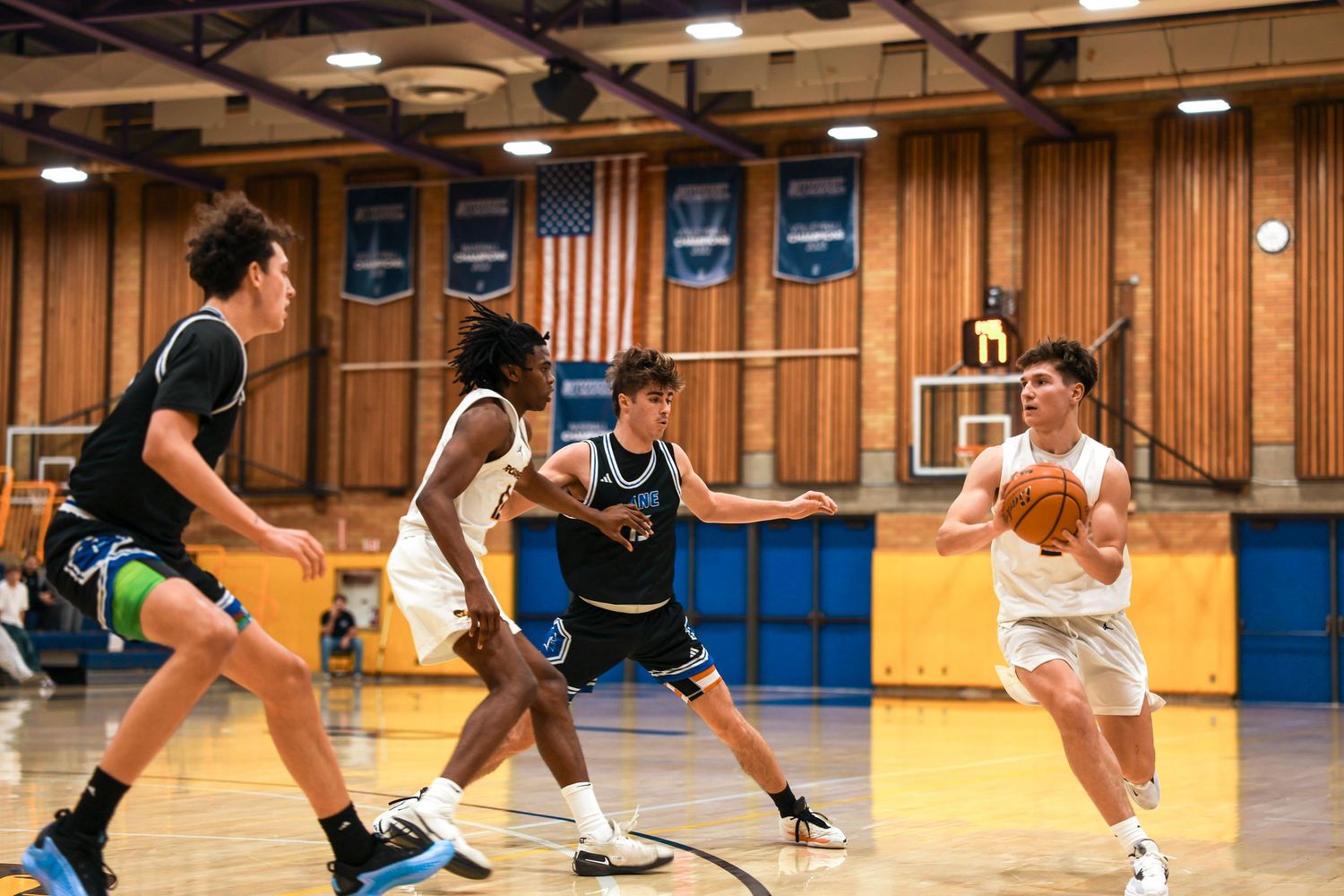 Players dive for a loose basketball during an intense game on the hardwood court.