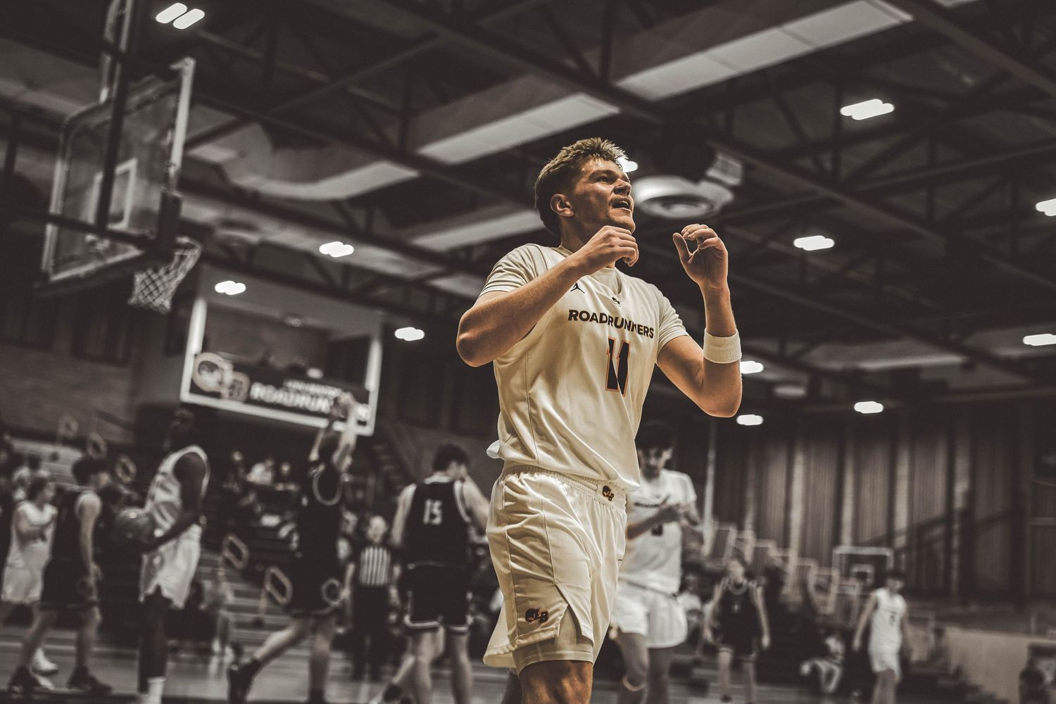 Basketball players leap high during gameplay in an indoor gymnasium setting.