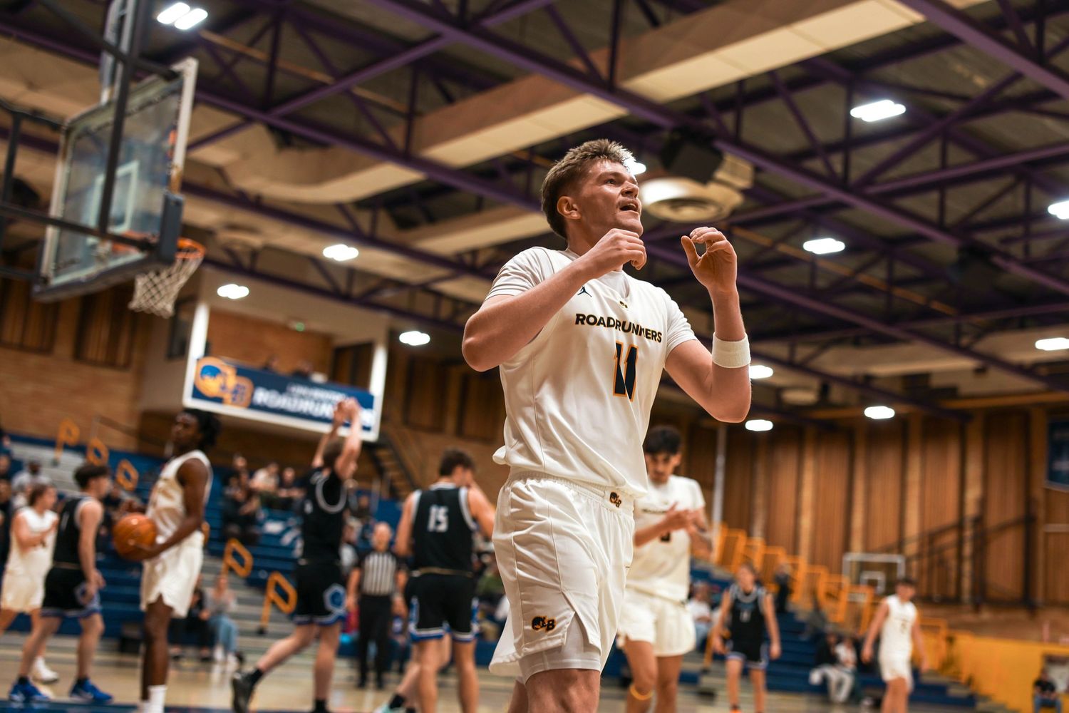Wide view of a basketball game in progress showing players and spectators in a gymnasium.