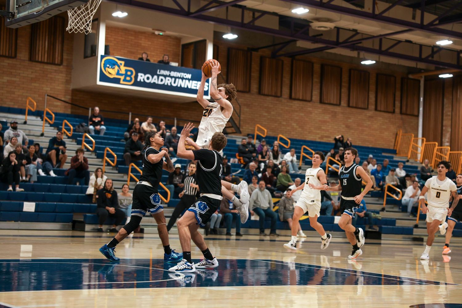 Wide angle view of basketball players in action on a gymnasium court.