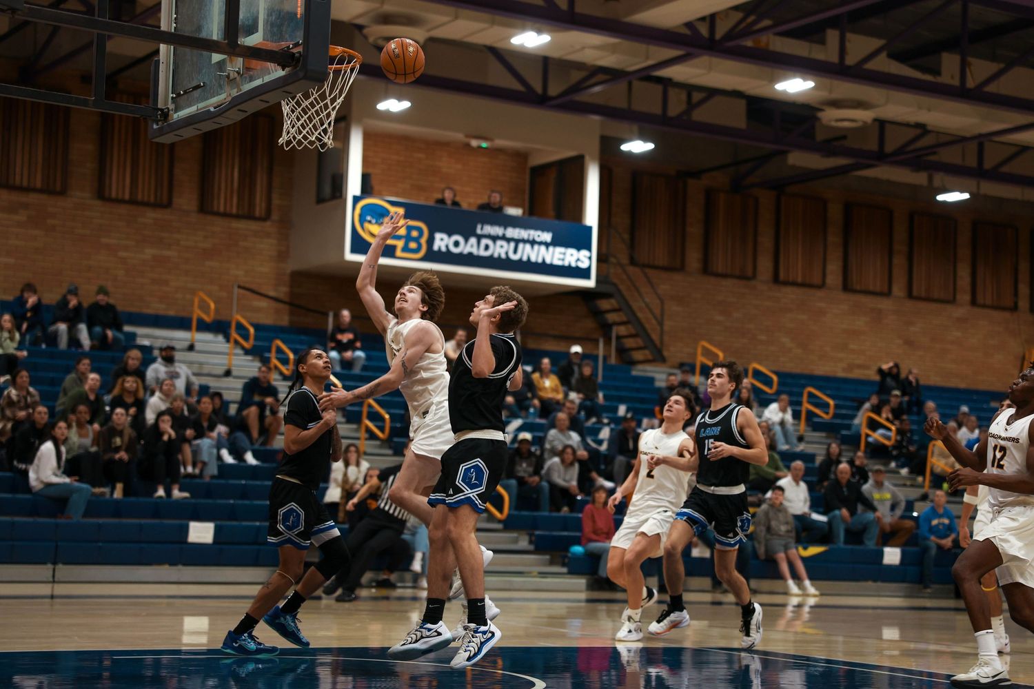 Basketball players battle for position during a competitive game play sequence.