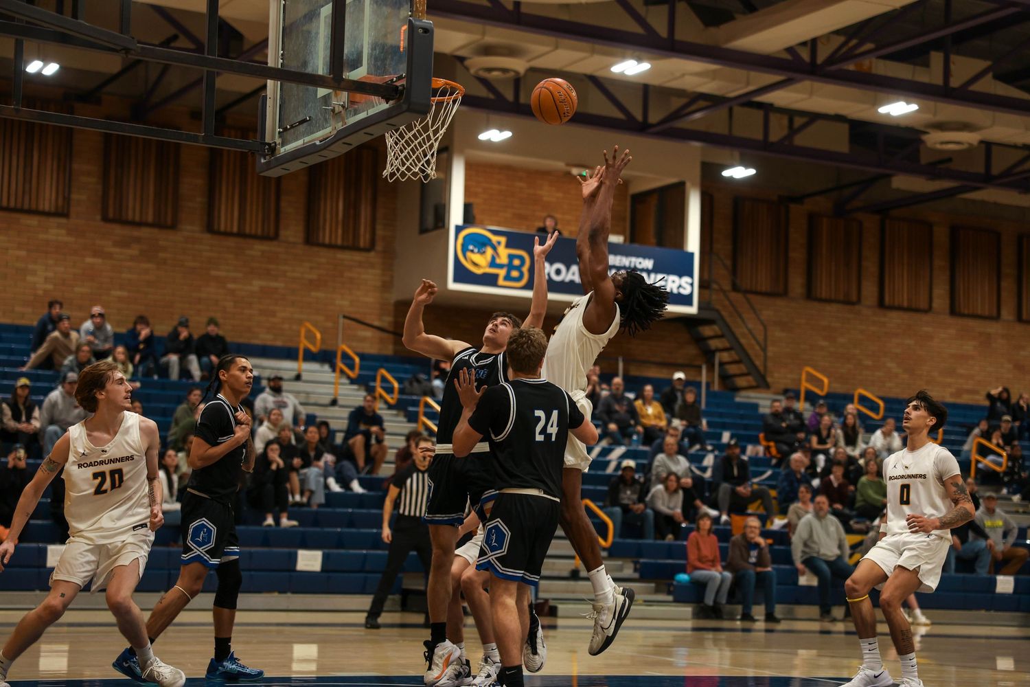Players jump for the ball during an intense basketball game moment.