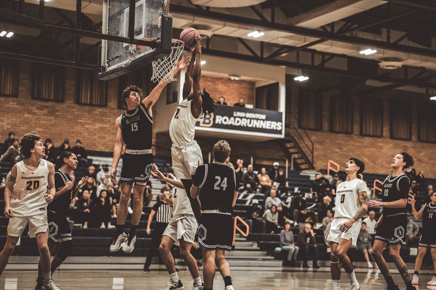 Basketball players leap high to compete for a rebound during an intense indoor game.